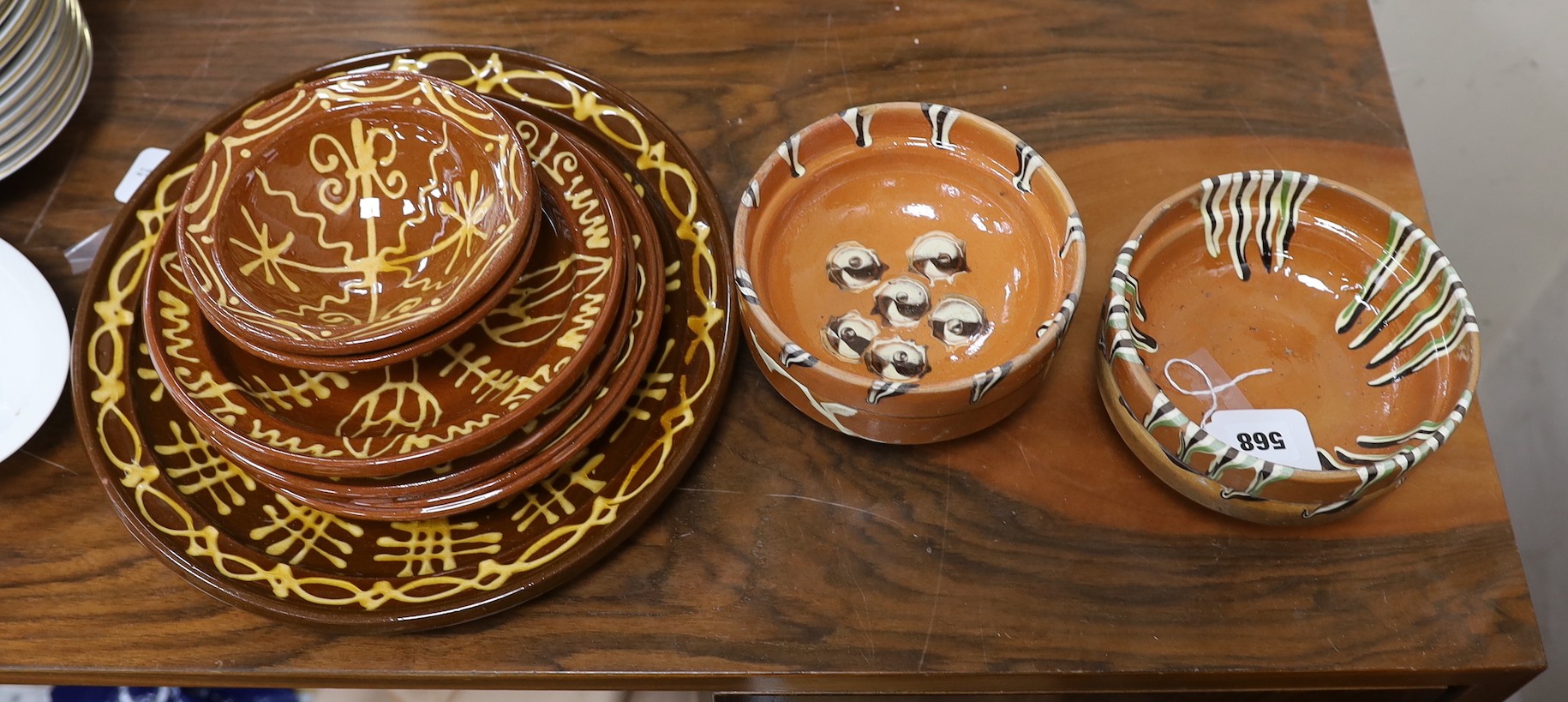 Four French pottery slip ware style pottery bowls and a pottery five similar dishes, largest 33cms diameter